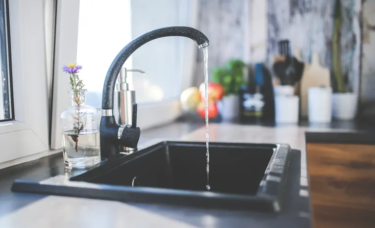 Water flowing from a modern kitchen tap into a sink